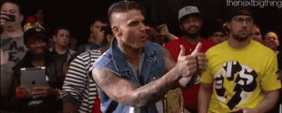 Man In Denim Vest Giving Thumbs Up In Crowd GIF