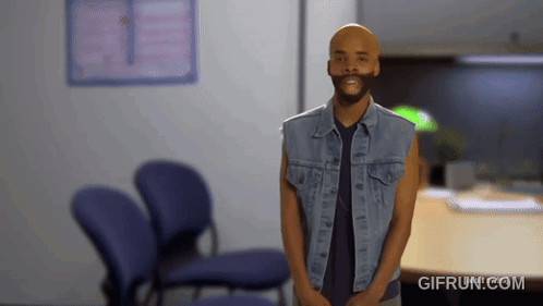 Man In Denim Vest Standing In Waiting Room GIF