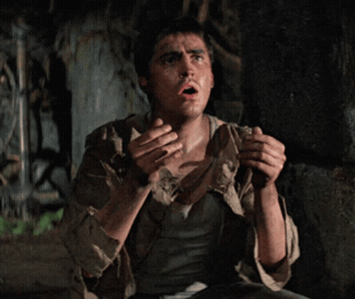 Man In Dirty Shirt Sitting In Dark Room With Mouth Open GIF