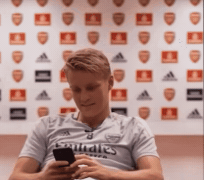 Man in Emirates Shirt Looking at Cell Phone