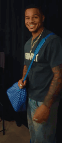 Man In Extrovert T-Shirt Smiling Holding Blue Bag GIF