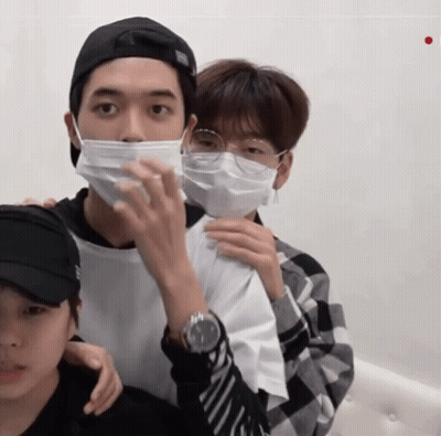 Man In Face Mask And Glasses Holding Another Man's Arm GIF