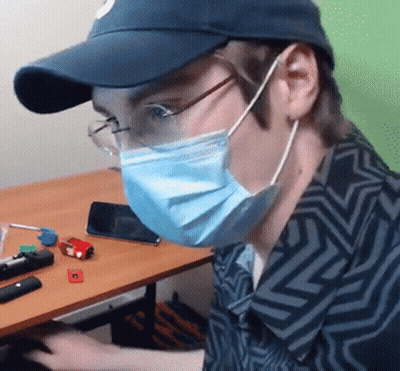 Man In Face Mask And Glasses Sitting At Table GIF