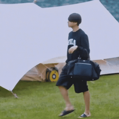 Man In Fila Shirt Walking With Duffel Bag GIF