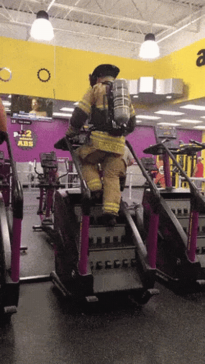 Man In Fireman Uniform Riding Treadmill At Gym GIF