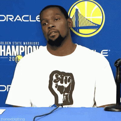 Man In Fist T-Shirt In Front Of Warriors Logo GIF