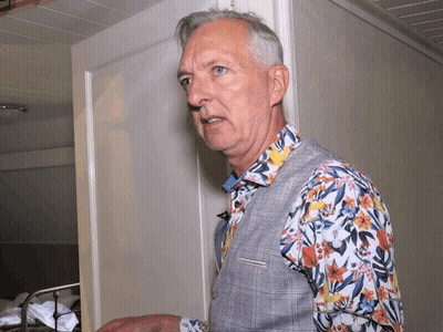 Man In Floral Shirt Standing In Front Of White Door GIF