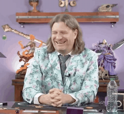 Man In Floral Suit Smiling With Folded Hands At Desk GIF