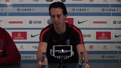 Man In Fly Emirates Shirt At Table With Water Bottles GIF