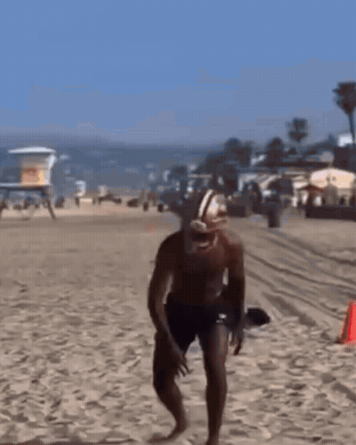 Man In Football Helmet And Shorts Running On Beach GIF