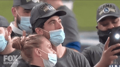 Man In Fox Deportes Hat Taking Selfie With Masked Woman GIF