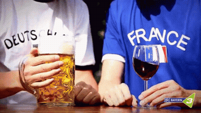 Man In France Shirt Holding Wine Next To Man In German Shirt GIF