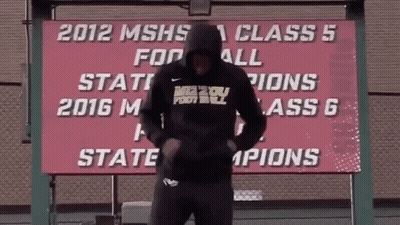 Man In Front Of 2012 MSHS Class 5 Football State Champions Sign GIF