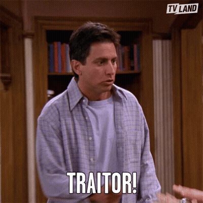 Man In Front Of Bookshelf Says Traitor GIF