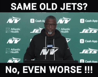Man In Front Of Green Backdrop With NY Jets Logos GIF