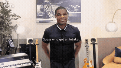 Man In Front Of Piano And Guitars Saying Guess Who Got An Intake GIF
