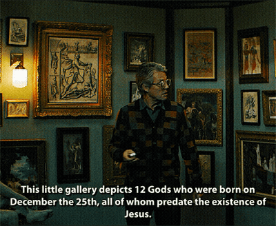Man In Front Of Wall Of Framed Pictures This Little Gallery Depicts 12 Gods Born On December GIF