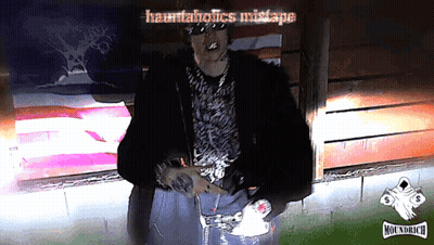Man In Fur Coat In Front Of Hauntedholics Mistake Sign GIF