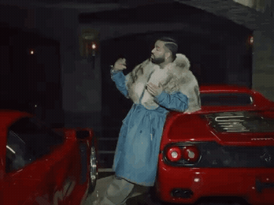 Man In Fur Coat Next To Red Sports Car GIF