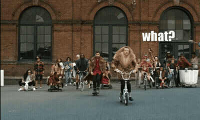 Man In Fur Coat Riding Bike Saying What GIF