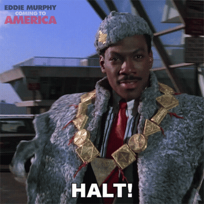 Man In Fur Coat Says Halt In Front Of Building GIF