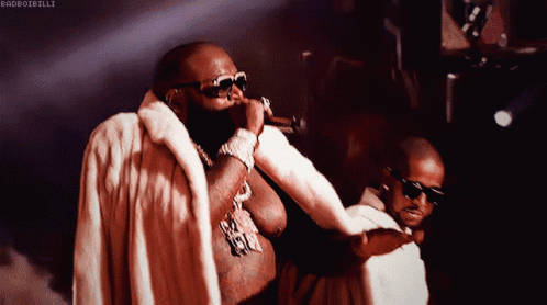 Man In Fur Coat Singing Into Microphone, Another Man Watching GIF