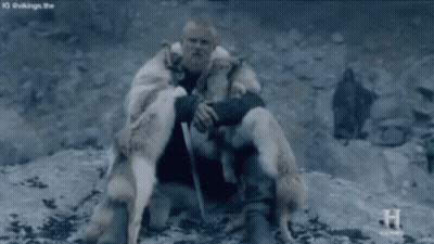 Man In Fur Coat Sitting On Rock Holding Sword GIF
