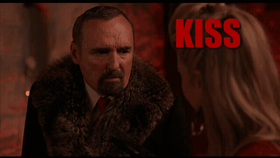 Man In Fur Coat Talking To Woman With Kiss Behind Him GIF