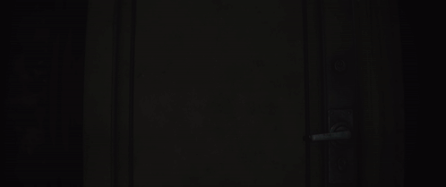 Man In Gas Mask With Yellow Eyes Standing In Dark Hallway GIF
