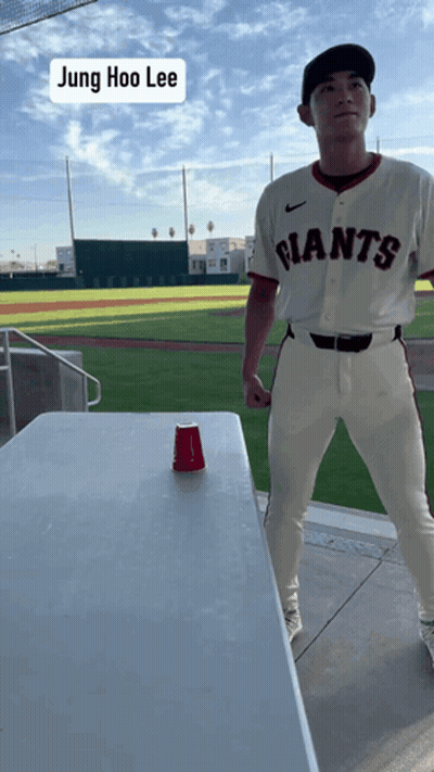 Man In Giants Jersey Standing By Table GIF