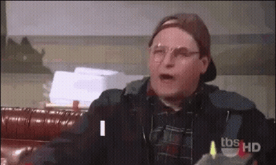 Man In Glasses And Baseball Cap Talking On Couch GIF