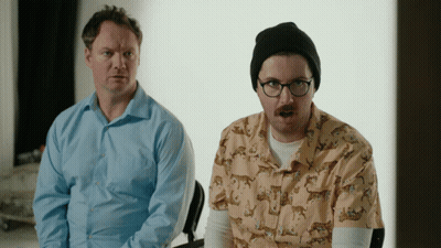 Man In Glasses And Beanie Next To Man In Leopard Print Shirt GIF