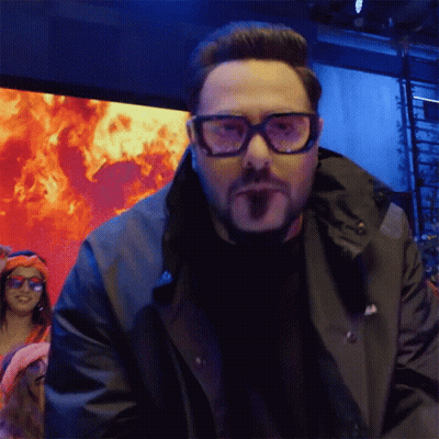 Man in Glasses and Black Jacket Facing Flames