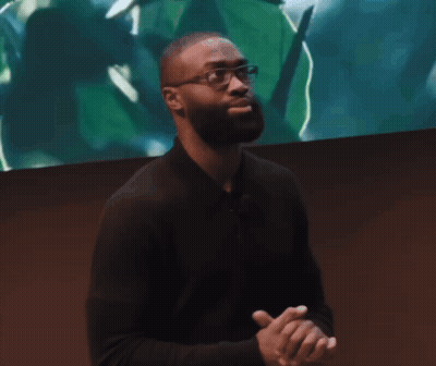Man In Glasses And Black Shirt In Front Of Screen With Green Leaf GIF