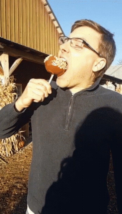 Man In Glasses And Black Sweater Eating Caramel Apple GIF