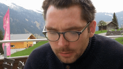 Man In Glasses And Black Sweater Looking Down GIF