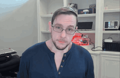 Man In Glasses And Blue Shirt In Front Of Bookcase GIF