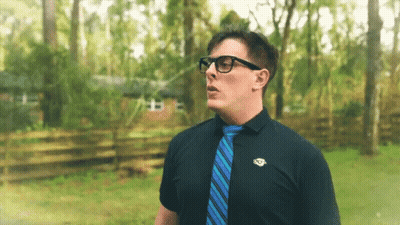 Man In Glasses And Blue Tie In Front Of House GIF