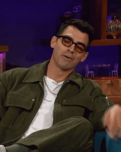 Man In Glasses And Green Jacket Sitting Down GIF