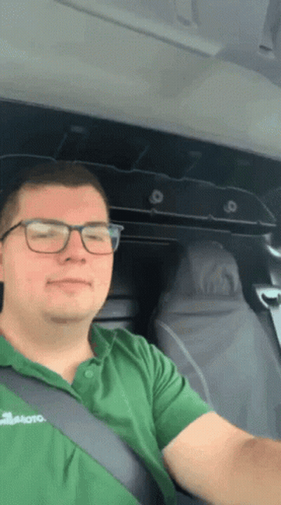 Man In Glasses And Green Shirt Sitting In Vehicle GIF