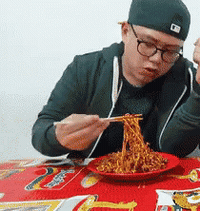 Man In Glasses And Hat Eating Noodles With Chopsticks GIF