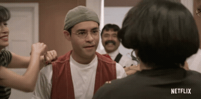 Man In Glasses And Hat Talking To Woman With Netflix Shirt GIF