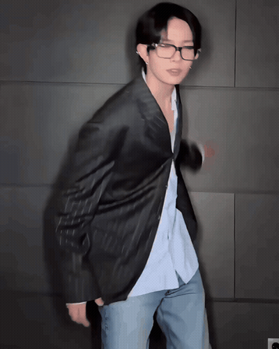 Man In Glasses And Jacket Standing In Front Of Wall GIF