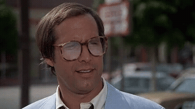 Man In Glasses And Light Blue Suit In Front Of No Parking Sign GIF