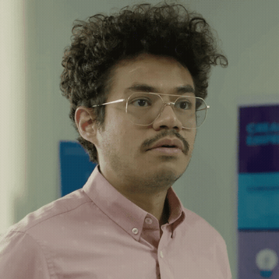 Man In Glasses And Pink Shirt In Front Of Blue And Purple Sign GIF