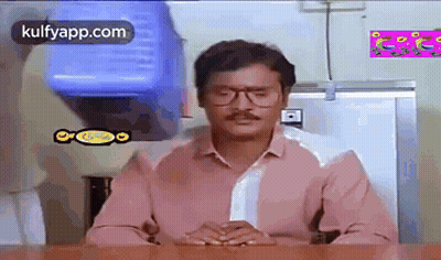 Man In Glasses And Pink Shirt Sitting At Table GIF