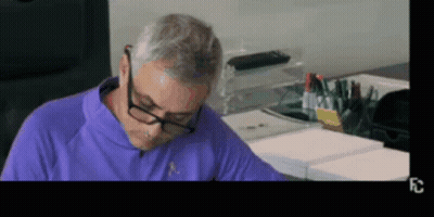 Man In Glasses And Purple Shirt Sitting At Table GIF