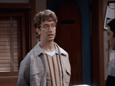 Man In Glasses And Striped Shirt In Front Of Door GIF