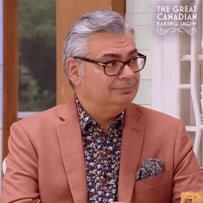 Man In Glasses And Suit In Front Of Great Canadian Baking Show Sign GIF