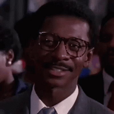 Man In Glasses And Suit Smiling In Crowd GIF